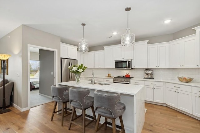 kitchen with decorative backsplash, appliances with stainless steel finishes, light wood-style floors, white cabinets, and a sink