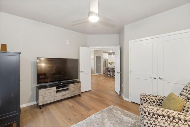 living room featuring light wood-style floors, ceiling fan, and baseboards