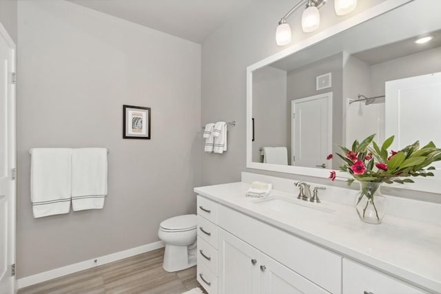 bathroom with toilet, baseboards, wood finished floors, and vanity