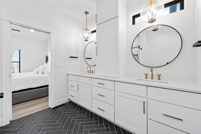 ensuite bathroom with double vanity, ensuite bath, a sink, and baseboards