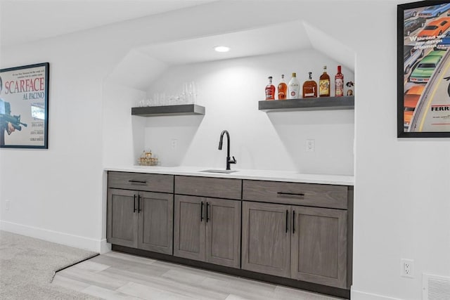 bar featuring visible vents, wet bar, baseboards, and a sink