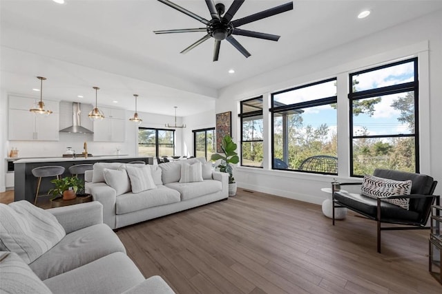 living area featuring baseboards, wood finished floors, a ceiling fan, and recessed lighting