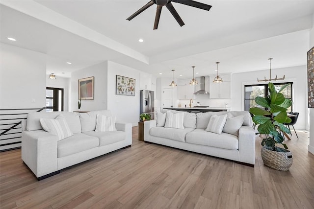 living area featuring ceiling fan with notable chandelier, wood finished floors, and recessed lighting