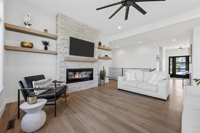 living room with a fireplace, visible vents, wood finished floors, and recessed lighting