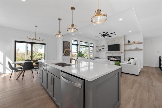 kitchen with a fireplace, a sink, light wood-style floors, stainless steel dishwasher, and gray cabinets