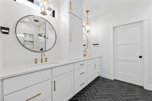 full bath with baseboards, a sink, a marble finish shower, and double vanity