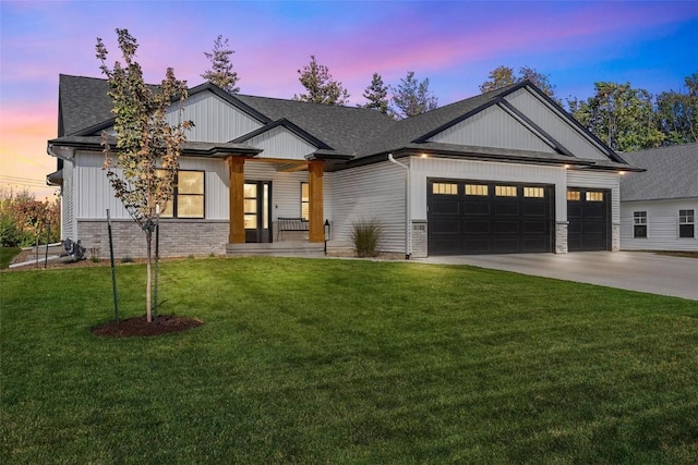 view of front of property featuring brick siding, roof with shingles, an attached garage, a front yard, and driveway