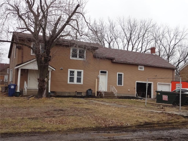 view of front facade featuring entry steps, a garage, and a chimney