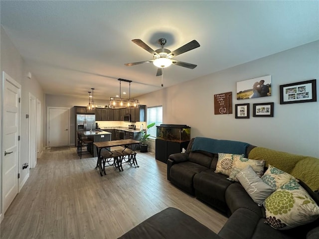 living room with light wood-type flooring and ceiling fan with notable chandelier