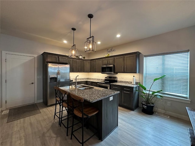 kitchen with dark stone countertops, a sink, stainless steel appliances, a kitchen bar, and backsplash