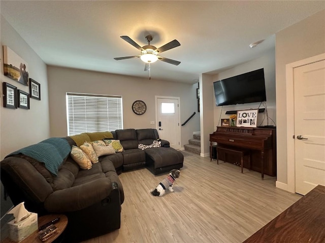 living room with baseboards, stairway, a ceiling fan, and light wood-style floors