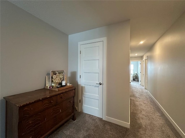 corridor featuring baseboards and carpet flooring