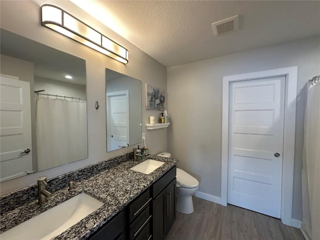 bathroom with toilet, visible vents, a sink, and wood finished floors