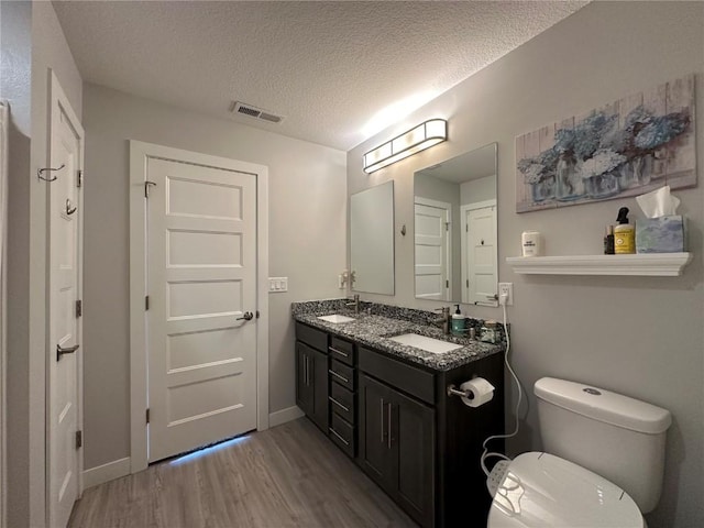 bathroom featuring visible vents, wood finished floors, a sink, and toilet