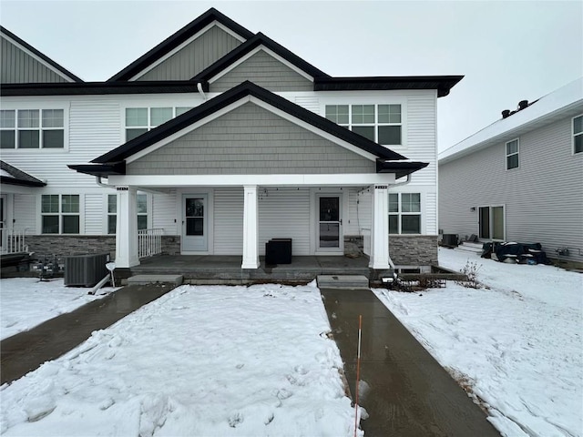 view of front of home with covered porch, stone siding, board and batten siding, and central air condition unit