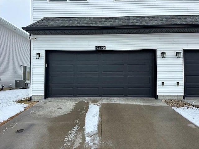 garage with concrete driveway and central AC unit