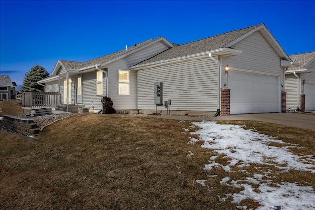 snow covered property featuring a garage, driveway, and a lawn