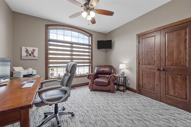 carpeted office space with ceiling fan and baseboards