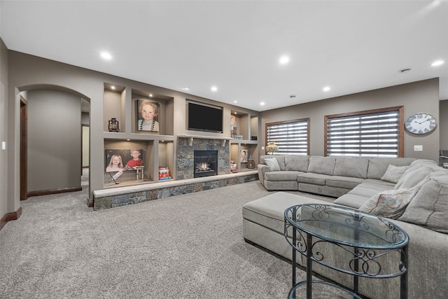 carpeted living area with recessed lighting, built in shelves, and a stone fireplace