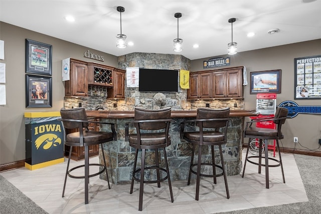 bar with hanging light fixtures, tasteful backsplash, and wet bar