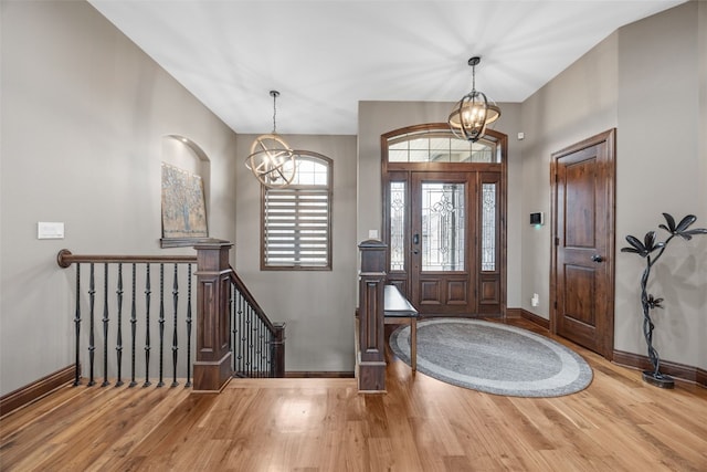 entrance foyer featuring a notable chandelier, baseboards, and wood finished floors