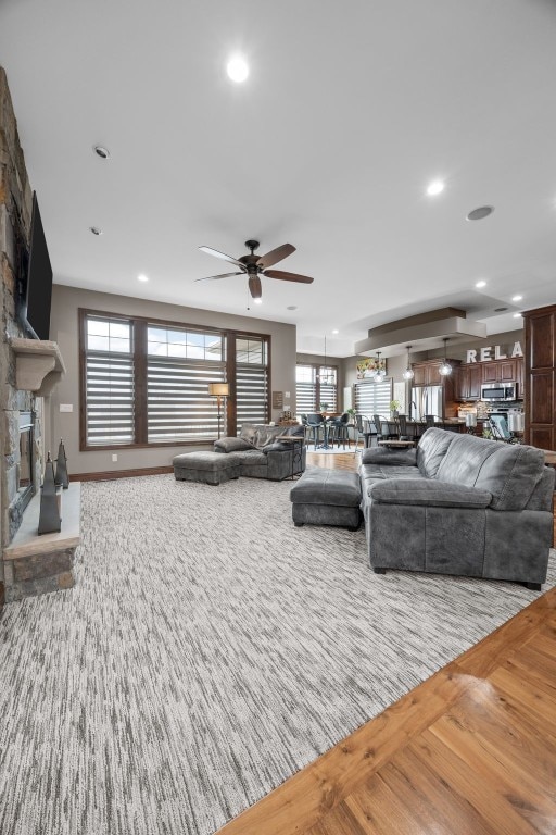 living room with ceiling fan, recessed lighting, a fireplace, and wood finished floors