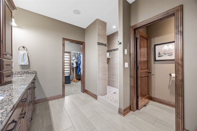 bathroom with baseboards, a walk in shower, and vanity