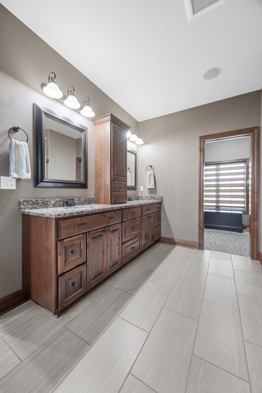 full bath featuring visible vents, baseboards, and double vanity