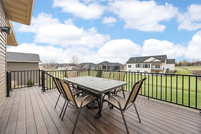 wooden terrace featuring a residential view, outdoor dining area, and a lawn