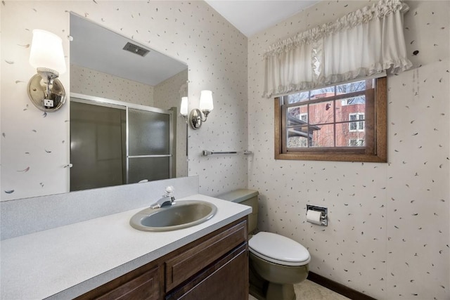 bathroom with toilet, a stall shower, vanity, and wallpapered walls