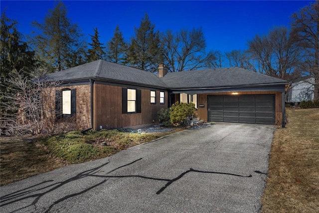 ranch-style home with a garage, driveway, a chimney, and a shingled roof