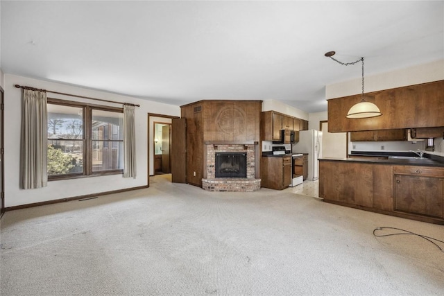 unfurnished living room with a brick fireplace, baseboards, visible vents, and light colored carpet