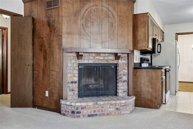 kitchen featuring electric range, visible vents, light colored carpet, stainless steel microwave, and a fireplace