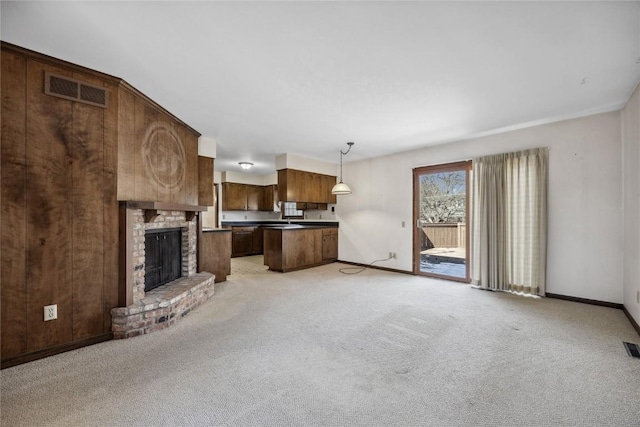 unfurnished living room featuring baseboards, a fireplace, visible vents, and light colored carpet