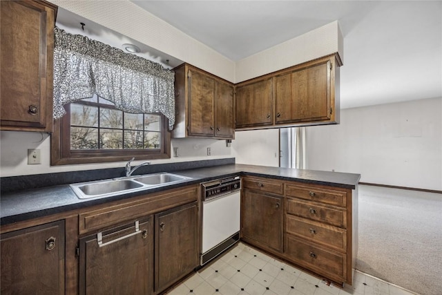 kitchen featuring light floors, dark countertops, dark brown cabinetry, white dishwasher, and a sink