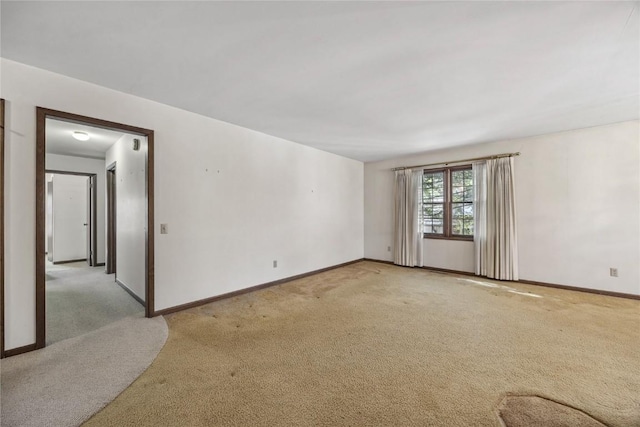 empty room featuring light carpet and baseboards