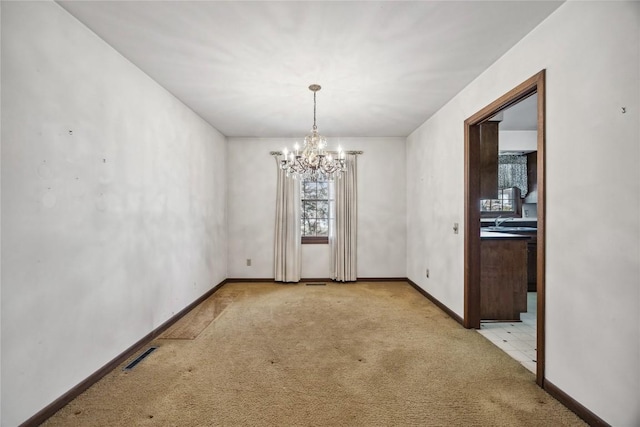 empty room featuring an inviting chandelier, baseboards, visible vents, and light colored carpet