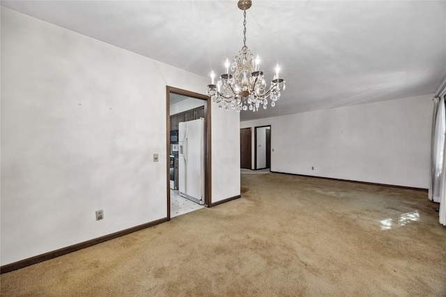 carpeted empty room featuring baseboards and a chandelier