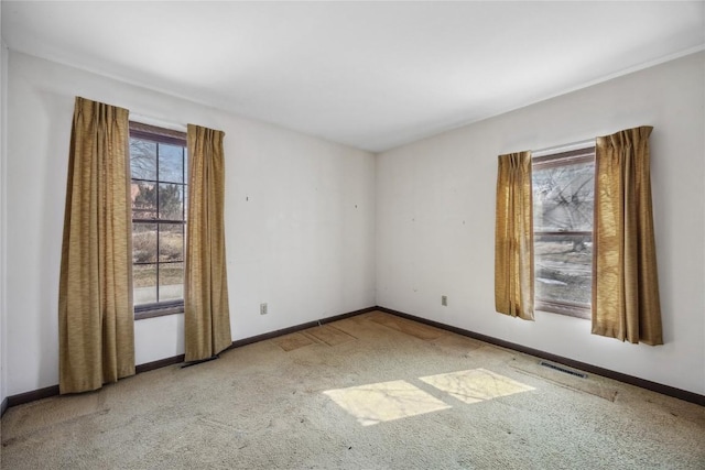 unfurnished room with carpet, visible vents, and baseboards