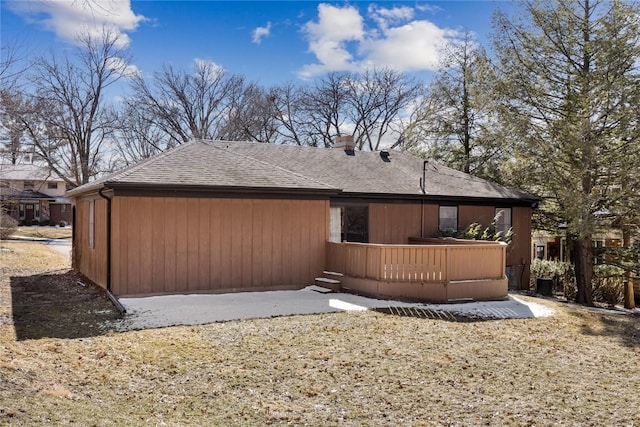 view of side of property with roof with shingles and a wooden deck