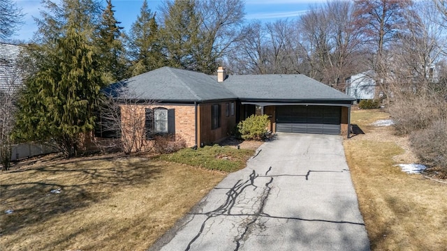 ranch-style home with driveway, brick siding, a chimney, an attached garage, and a front yard