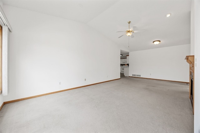 unfurnished living room with lofted ceiling, ceiling fan, carpet floors, a fireplace, and visible vents