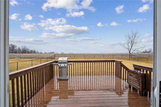 wooden deck with a rural view, a fenced backyard, and a grill