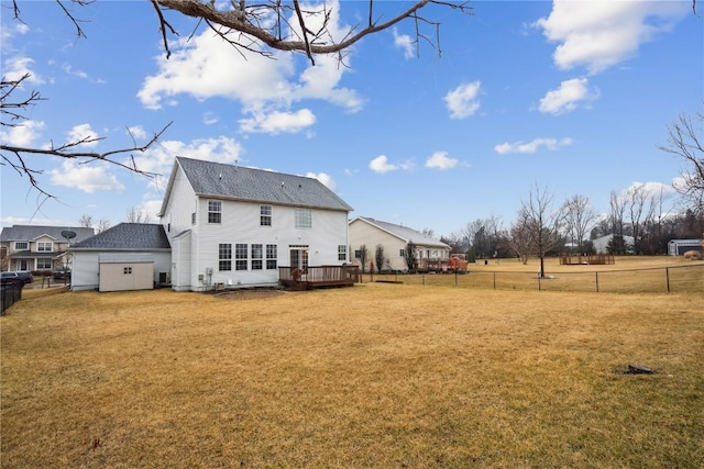 rear view of property featuring roof with shingles, a lawn, fence, and a wooden deck