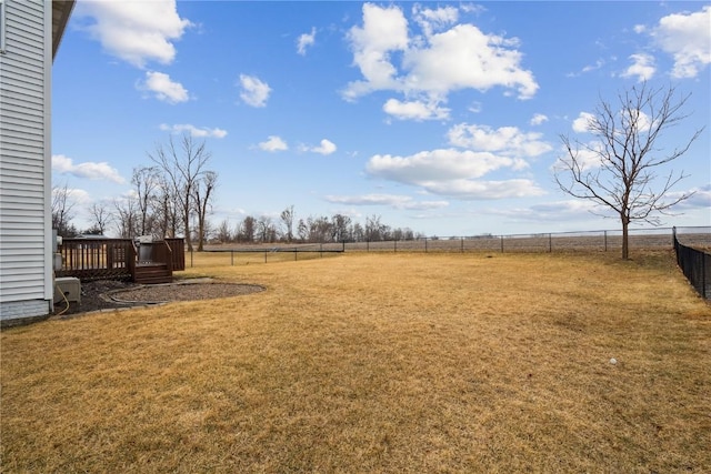 view of yard with a rural view, fence, and a wooden deck