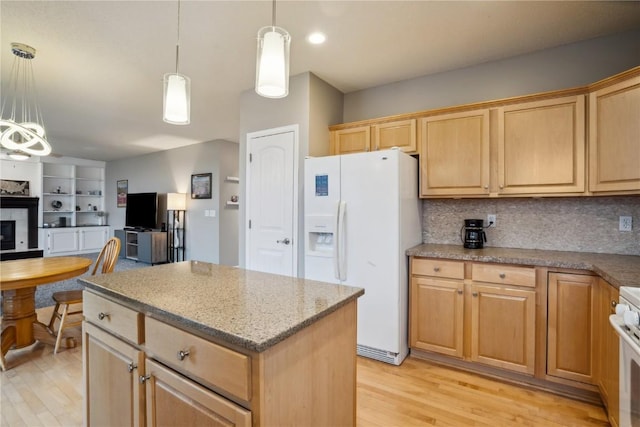 kitchen with white appliances, a fireplace, a kitchen island, open floor plan, and light wood-type flooring