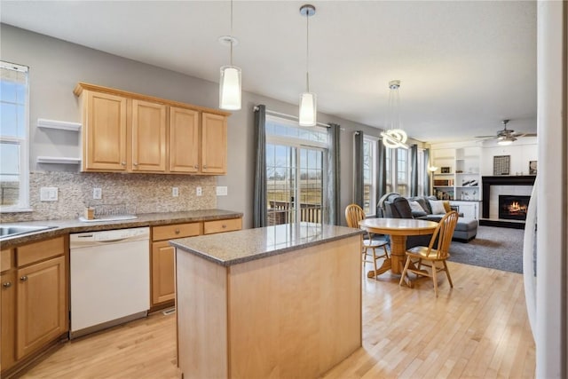 kitchen featuring a healthy amount of sunlight, light brown cabinets, a fireplace, and dishwasher