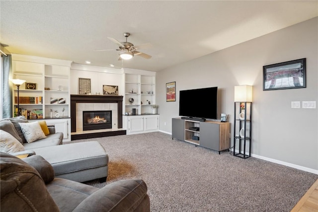 carpeted living area with ceiling fan, a fireplace, and baseboards