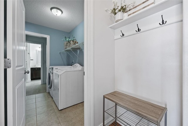 laundry area with laundry area, light tile patterned floors, separate washer and dryer, and a textured ceiling