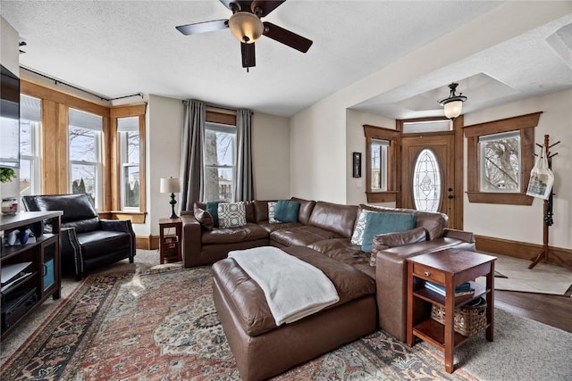 living area with ceiling fan, a textured ceiling, baseboards, and wood finished floors